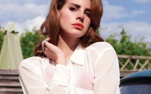 HD PC desktop wallpaper featuring Lana Del Rey in a white blouse, set against a bright outdoor background, embodying music and cinematic style.