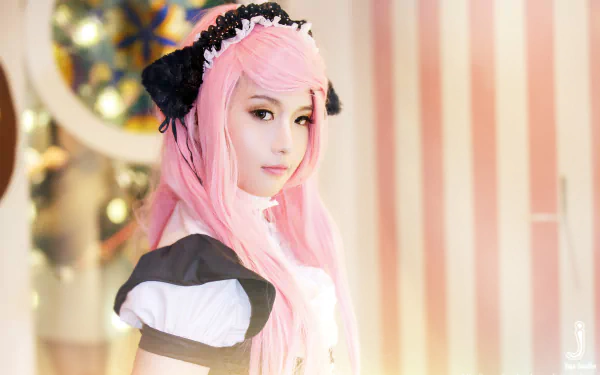 A Vietnamese woman with pink hair in a cosplay outfit poses against a softly lit, striped background, capturing a whimsical and enchanting atmosphere.