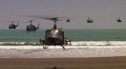 A dramatic scene from *Apocalypse Now*, featuring helicopters flying over a beach with crashing waves, set against a serene sea backdrop in this HD desktop wallpaper.