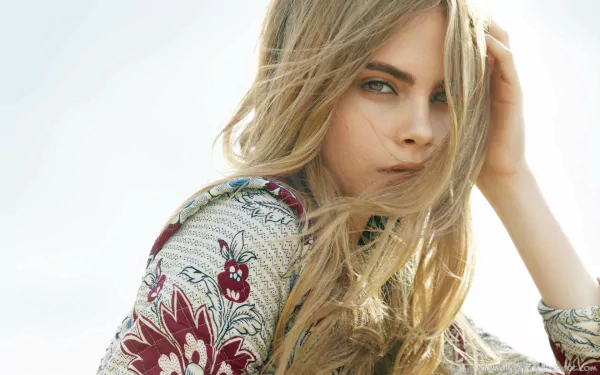 A striking HD desktop wallpaper featuring celebrity Cara Delevingne, showcasing her captivating gaze and flowing hair against a soft background.