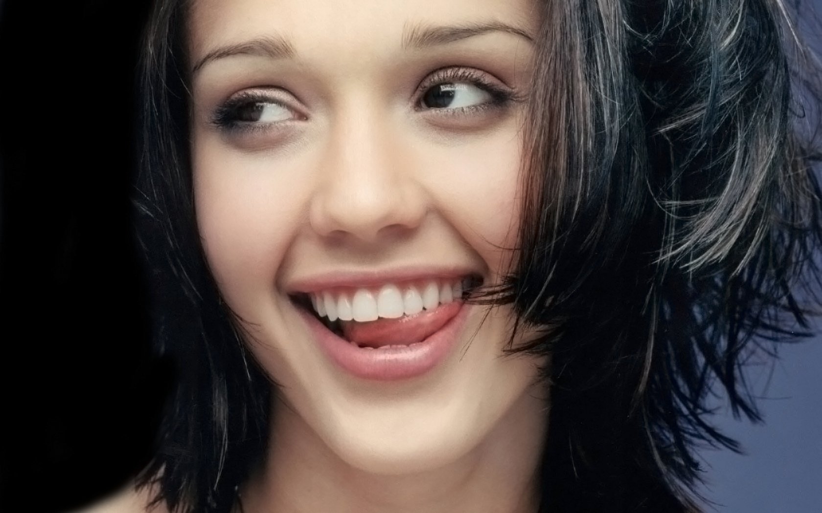 Close-up HD PC desktop wallpaper of celebrity Jessica Alba smiling with dark hair and expressive eyes against a blurred background.
