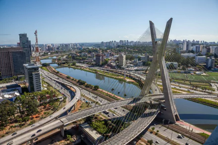 Aerial view of the Octávio Frias de Oliveira Bridge in São Paulo, Brazil, showcasing its unique design and the surrounding urban landscape. Man-made structure against a clear sky.