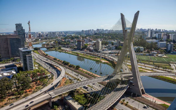 Aerial view of the Octávio Frias de Oliveira Bridge in São Paulo, Brazil, showcasing its unique design and the surrounding urban landscape. Man-made structure against a clear sky.