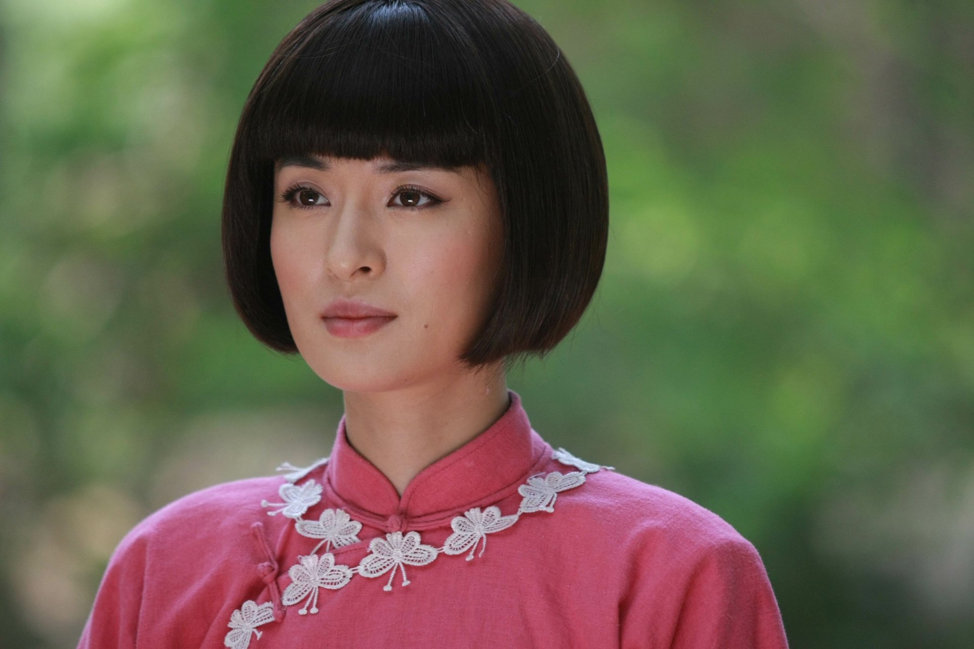 Portrait of an Asian woman with a sleek bob haircut wearing a pink traditional dress, set against a soft bokeh background in 4K Ultra HD quality.