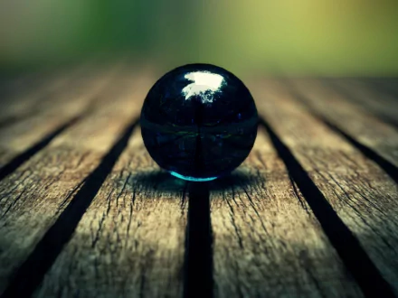 Close-up of a blue marble globe resting on textured wooden planks, captured in high-definition photography for a nature-inspired PC desktop wallpaper.