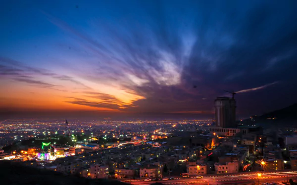 A stunning sunset over Tehran, Iran, showcases a vibrant city skyline under a dramatic sky, transitioning from twilight to night, captured in 4K Ultra HD.