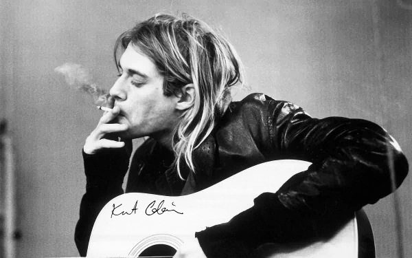 Black and white HD desktop wallpaper featuring musician Kurt Cobain smoking while holding an acoustic guitar.