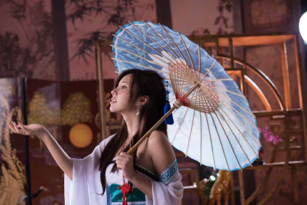 A Taiwanese model, Chén Sīyǐng, poses gracefully with a blue umbrella, showcasing elegance against a cultural backdrop, creating a captivating HD desktop wallpaper.