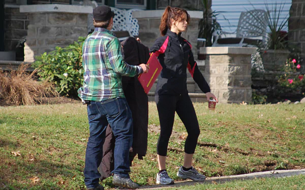 HD desktop wallpaper featuring Jennifer Lawrence in a casual scene from the movie Silver Linings Playbook, set outdoors with greenery and a stone house background.