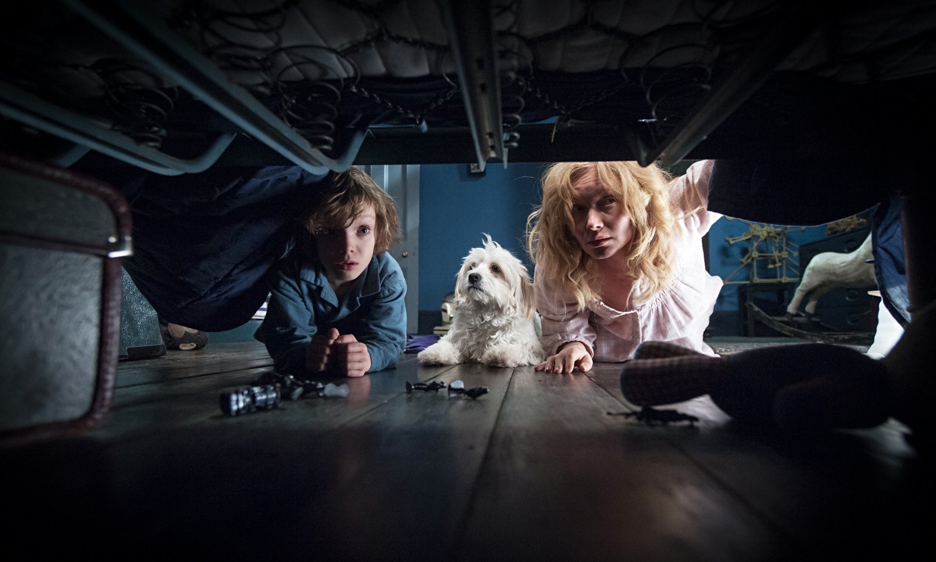HD desktop wallpaper featuring Essie Davis and Noah Wiseman from the movie The Babadook, peering under a bed with a white dog between them.