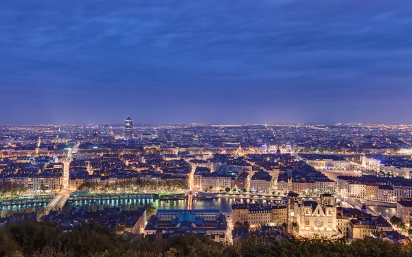 Panoramic 4K Ultra HD view of Lyon, France at dusk, showcasing the city’s illuminated architecture and river under a deep blue sky.