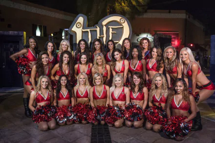 Tampa Bay cheerleaders posing together at night, wearing red and black uniforms with pom-poms, captured in a vibrant HD sports-themed desktop wallpaper.