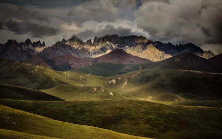 HD desktop wallpaper featuring the jagged peaks of the Bayan Har Mountains in Sichuan, China, under a dramatic sunset-lit sky.