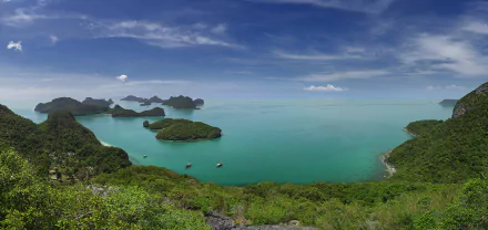 Panoramic 4K Ultra HD view of Ang Thong's tropical lagoon and islets in Thailand, showcasing vibrant sea, lush greenery, and a vast blue sky over the ocean.