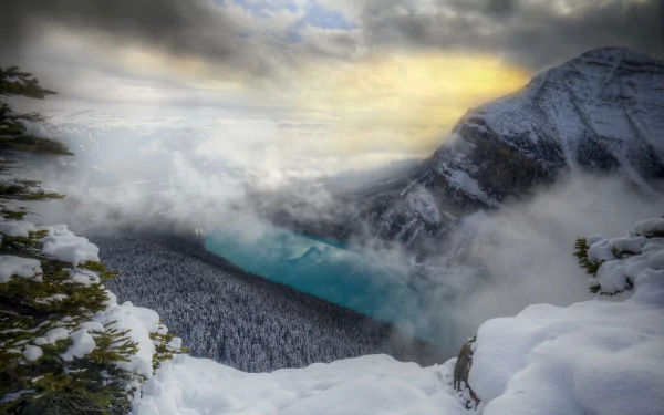 A stunning winter landscape in Banff National Park, Alberta, Canada, featuring snow-covered mountains, a tranquil lake, and soft clouds illuminated by a glowing sunset.