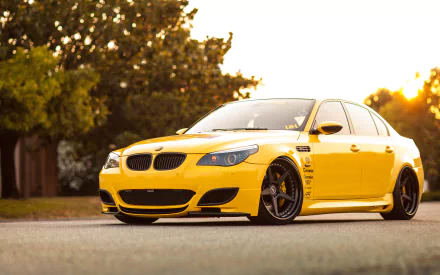 A striking yellow BMW M5 is showcased against a sunset backdrop, highlighting its sleek design and performance. This HD image serves as an engaging desktop wallpaper.