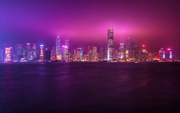 4K Ultra HD night skyline of Hong Kong's megapolis in China, featuring illuminated skyscrapers reflecting over the water under a vibrant purple-pink sky.
