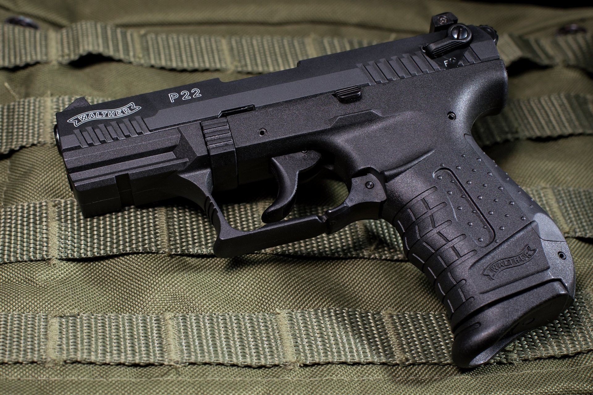 4K Ultra HD PC desktop wallpaper: close-up of a man-made Walther P22 pistol resting on olive tactical webbing, detailed view of the slide, grip, and trigger.