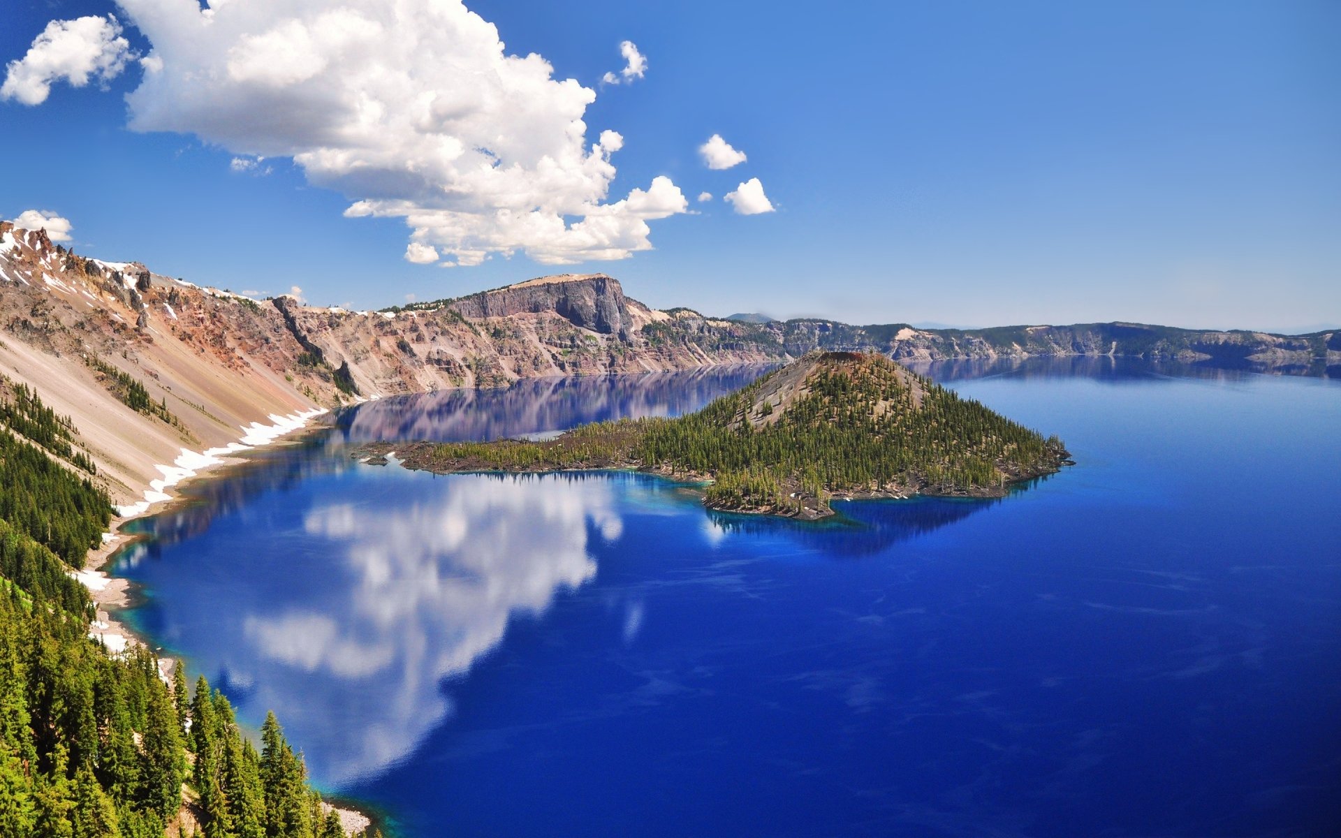 4K Ultra HD desktop wallpaper showcasing a serene lake surrounded by rugged cliffs, with a small island in the center under a bright blue sky with clouds.