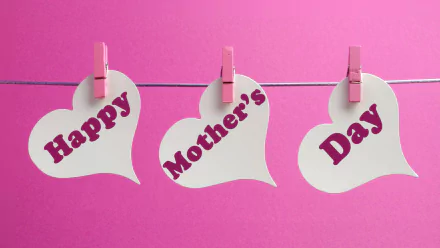 HD desktop wallpaper featuring three white heart-shaped notes clipped on a string with pink clothespins, each displaying the words Happy Mother's Day on a pink background.