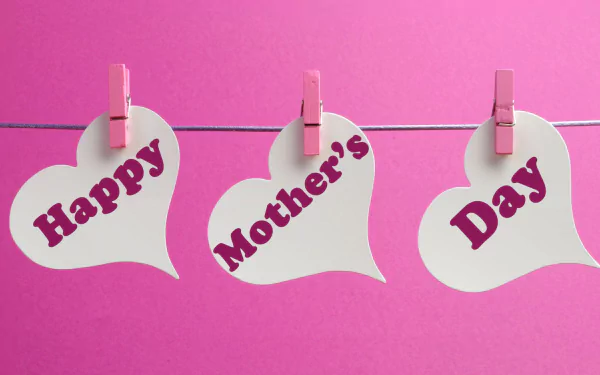 HD desktop wallpaper featuring three white heart-shaped notes clipped on a string with pink clothespins, each displaying the words Happy Mother's Day on a pink background.
