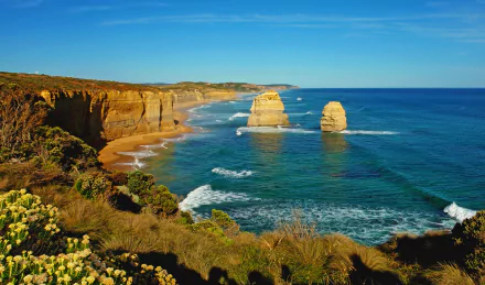 Scenic view of The Twelve Apostles limestone stacks along the coastline of Victoria, Australia, under a clear blue sky.