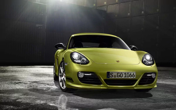 HD desktop wallpaper featuring a vibrant green Porsche Cayman R parked in a dimly lit industrial setting, showcasing the sleek design of this iconic sports car.