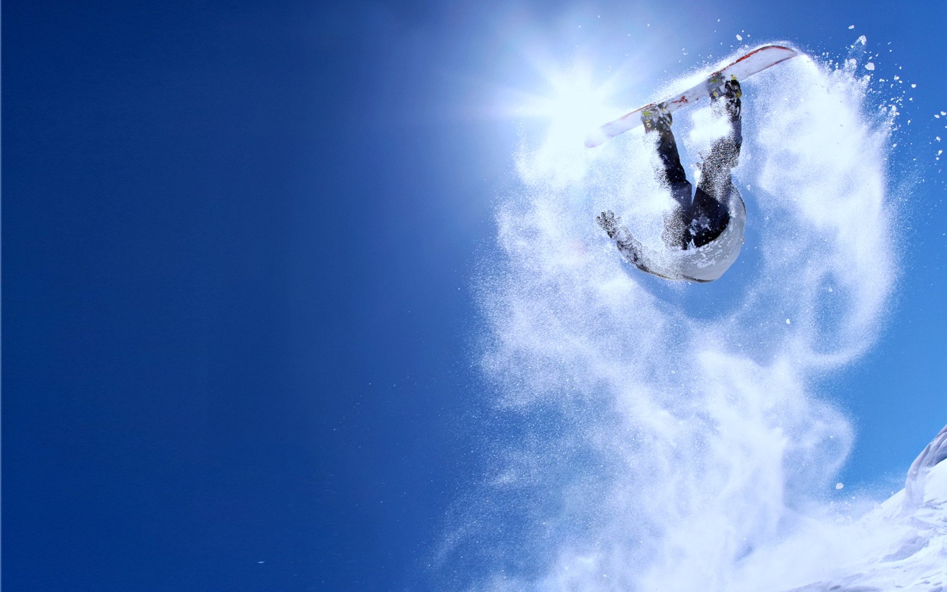 A snowboarder mid-flip in bright winter sunlight, kicking up snow against a clear blue sky. 4K Ultra HD PC desktop wallpaper showcasing dynamic snowboarding action.