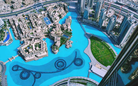 A high-definition desktop wallpaper showcasing an aerial view of Dubai, with modern skyscrapers, a luxurious hotel, and a stunning pool layout amidst the urban cityscape.