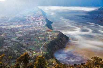 A breathtaking view of a fog-covered village nestled in a valley in Java, Indonesia, showcasing the serene landscape captured in stunning HD photography.
