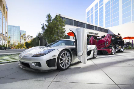 A striking image of a silver Pagani Huayra and Koenigsegg CCX, showcasing their sleek designs against a modern architectural backdrop. Perfect HD wallpaper for car enthusiasts.