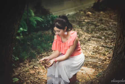 A Taiwanese model, Chén Sīyǐng, sits amidst fallen leaves in a serene outdoor setting, wearing a soft pink top and white skirt, capturing the essence of autumn.
