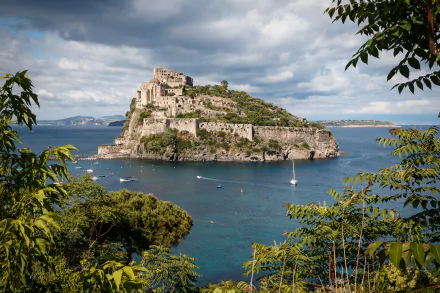 Aragonese Castle built on volcanic rock in the sea at Ischia, Gulf of Naples, Italy, captured in vivid 4K Ultra HD with green foliage framing the scene.
