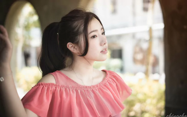 A beautiful Taiwanese model, Chén Sīyǐng, gazes thoughtfully in a soft-focus background, showcasing her serene expression and stylish pink outfit.