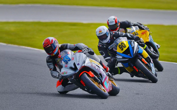 Three sportsbikes racing closely on a track, captured in sharp 4K Ultra HD detail, showcasing high-speed motorcycle competition.