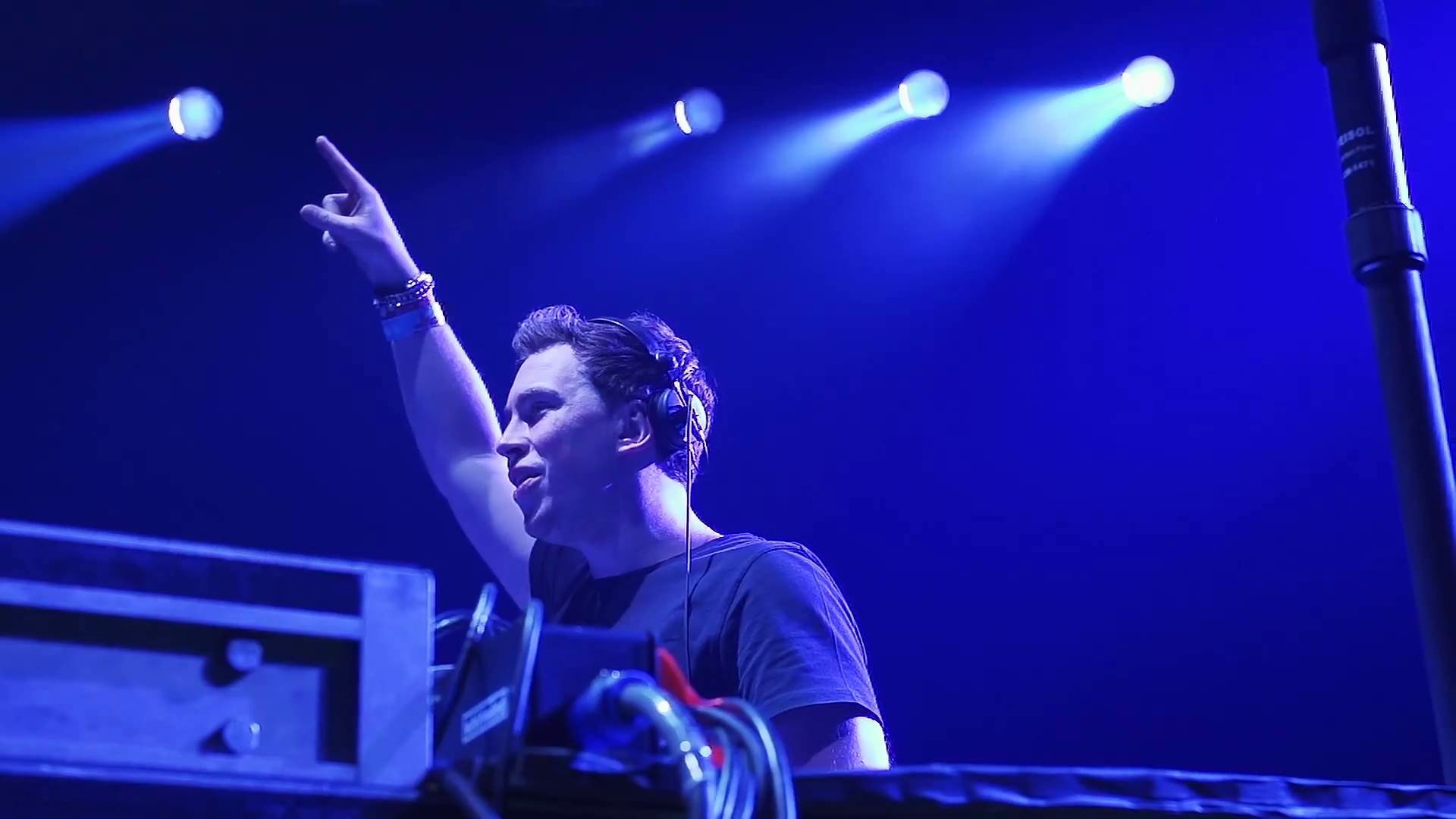 HD PC desktop wallpaper featuring Hardwell performing live, bathed in blue stage lighting, capturing the energy of electronic music.