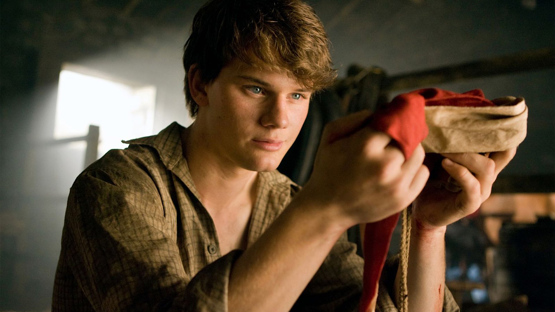 HD PC desktop wallpaper from the movie War Horse, featuring a young man intently holding a folded cloth in a dimly lit room.