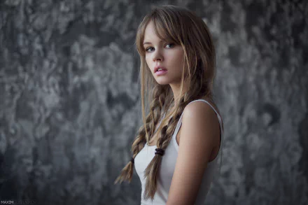 A brunette woman with braids stands against a textured gray background, enhanced by bokeh. This HD desktop wallpaper features model Anastasiya Scheglova in a white top.