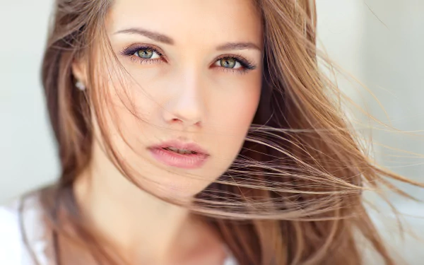 HD desktop wallpaper featuring a close-up of a woman model with windswept hair and an intense gaze.