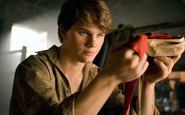 HD PC desktop wallpaper from the movie War Horse, featuring a young man intently holding a folded cloth in a dimly lit room.