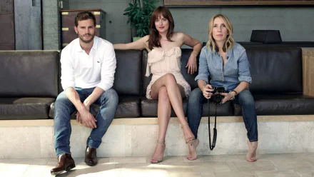 Jamie Dornan and Dakota Johnson, stars of the movie Fifty Shades of Grey, pose on a couch for a HD desktop wallpaper background.