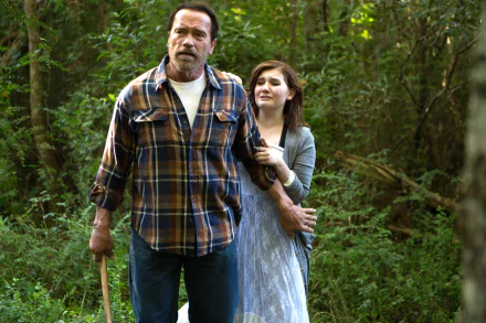 4K Ultra HD PC wallpaper: still from the movie Maggie (2015) — a rugged man with an axe walks through a green, sunlit forest while a young woman clings to his arm.