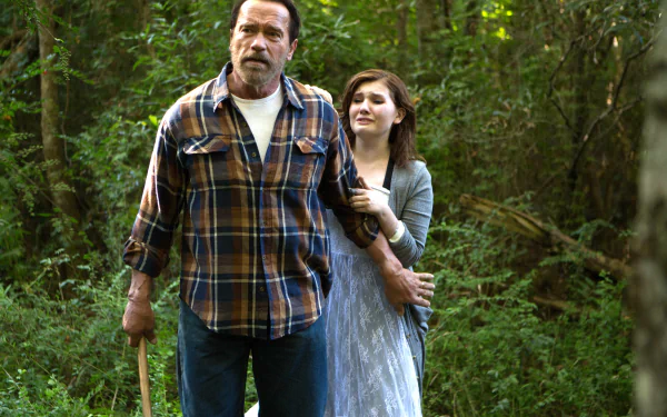 4K Ultra HD PC wallpaper: still from the movie Maggie (2015) — a rugged man with an axe walks through a green, sunlit forest while a young woman clings to his arm.