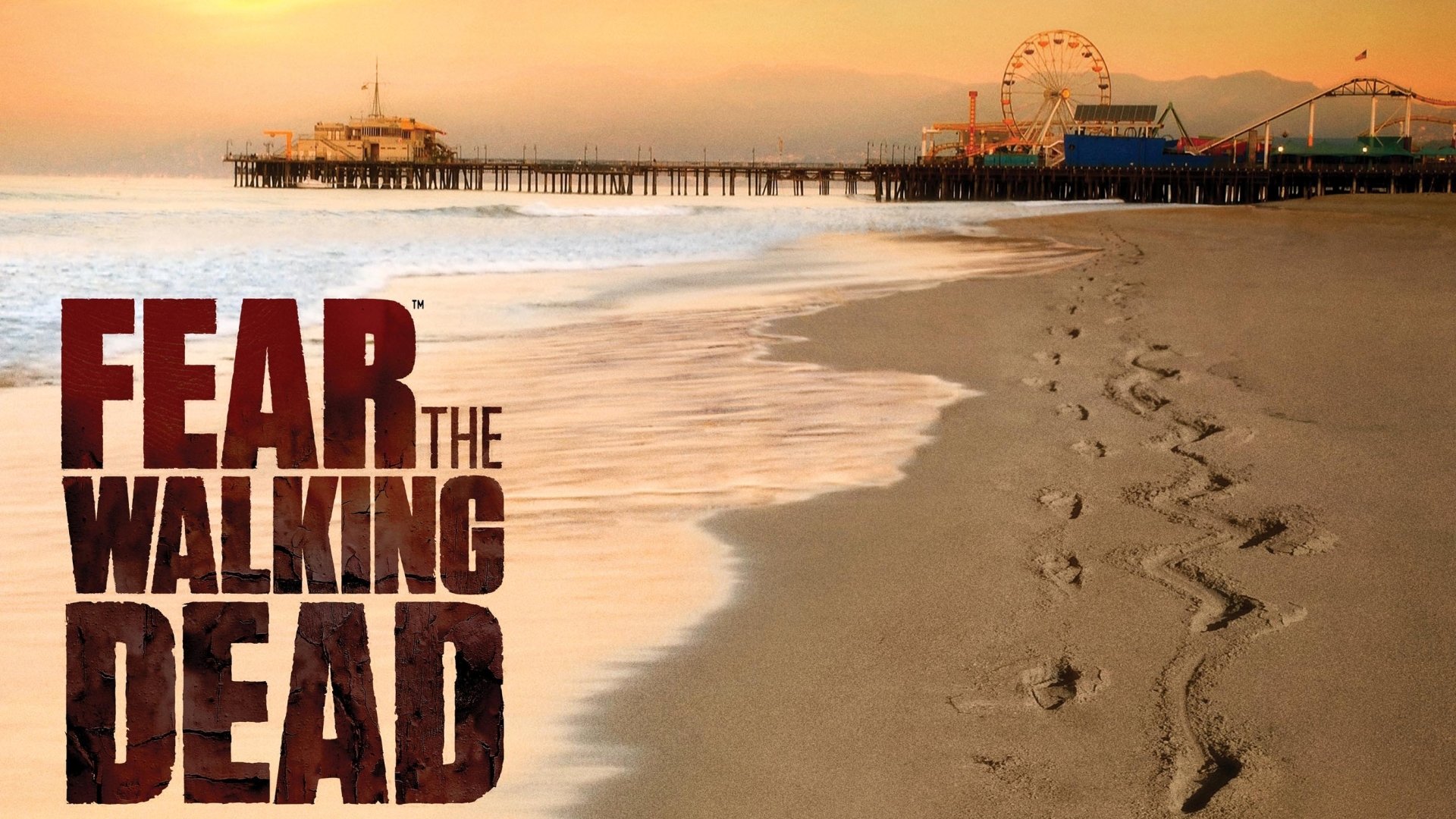 A serene beach scene at sunset features the title Fear the Walking Dead, blending horror themes with a peaceful coastal landscape as footsteps lead towards the ocean.