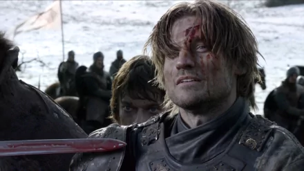 Game of Thrones HD wallpaper: bloodied Jaime Lannister in armor, grimacing on a snowy battlefield while Theon Greyjoy peers from behind.