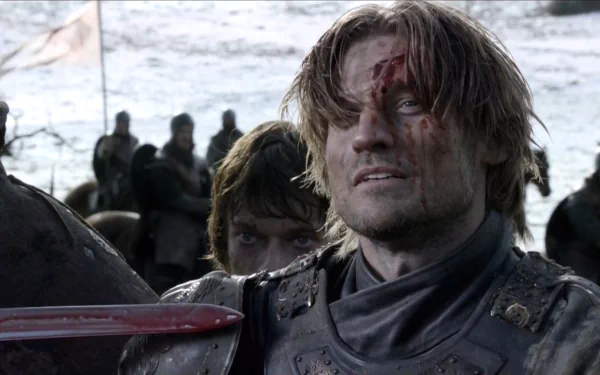 Game of Thrones HD wallpaper: bloodied Jaime Lannister in armor, grimacing on a snowy battlefield while Theon Greyjoy peers from behind.