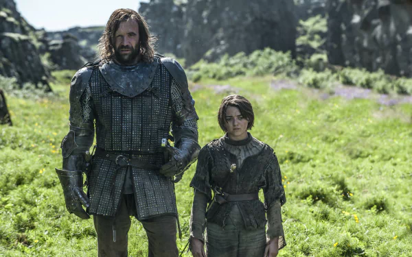 Arya Stark, portrayed by Maisie Williams, stands beside Sandor Clegane, played by Rory McCann, in a scene from Game of Thrones, set against a lush, green backdrop.