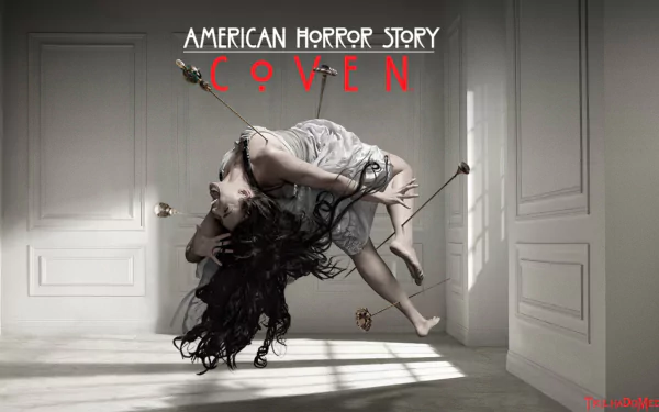 A haunting scene from *American Horror Story: Coven*, featuring a woman suspended in mid-air, conveying a sense of eerie tension in a stark, minimalist room.
