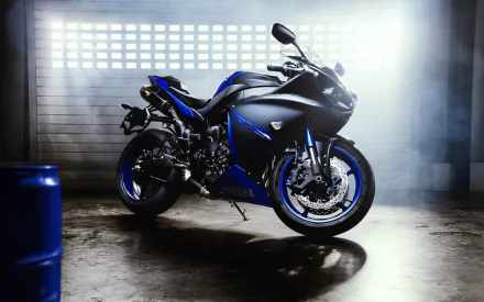 HD PC desktop wallpaper/background of a Yamaha YZF-R1 vehicle — a black and blue sport motorcycle parked in a dim industrial garage with dramatic side lighting and a reflective floor.