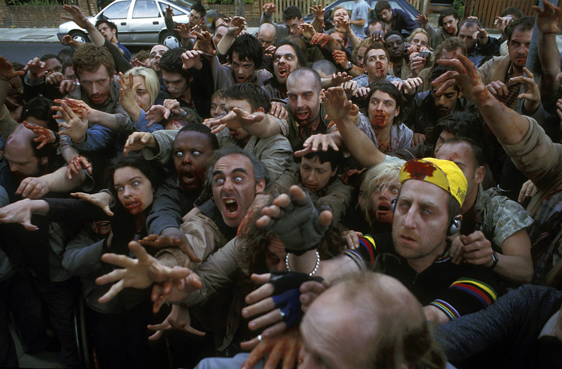 HD PC desktop wallpaper from the movie Shaun of the Dead: a dense horde of zombies pressing toward the viewer on a chaotic city street.